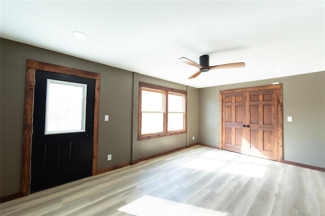 foyer with light wood-style flooring, a ceiling fan, and baseboards