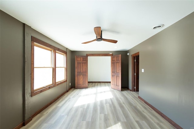 unfurnished room with visible vents, baseboards, light wood-style floors, and a ceiling fan