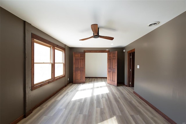 spare room with visible vents, baseboards, light wood-style floors, and a ceiling fan