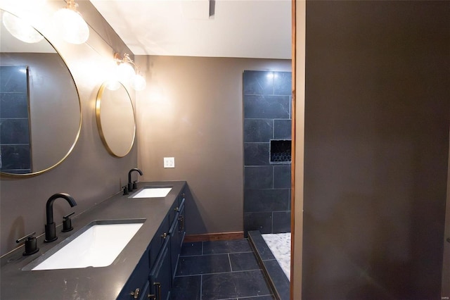 bathroom featuring a sink, a tile shower, double vanity, and tile patterned flooring