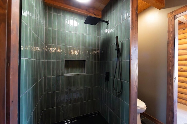 bathroom with a tile shower and toilet