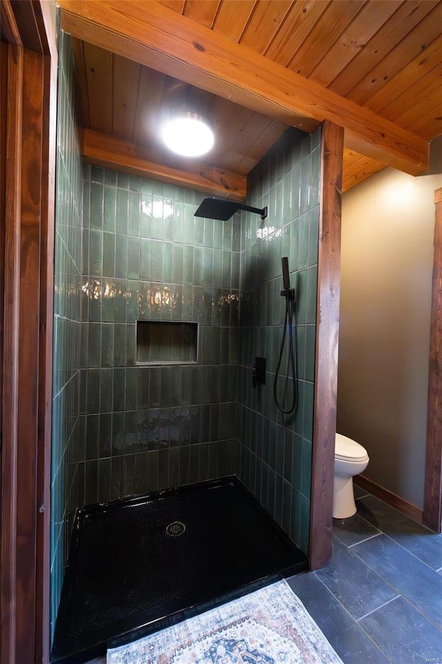 full bathroom featuring baseboards, beamed ceiling, toilet, wooden ceiling, and tiled shower