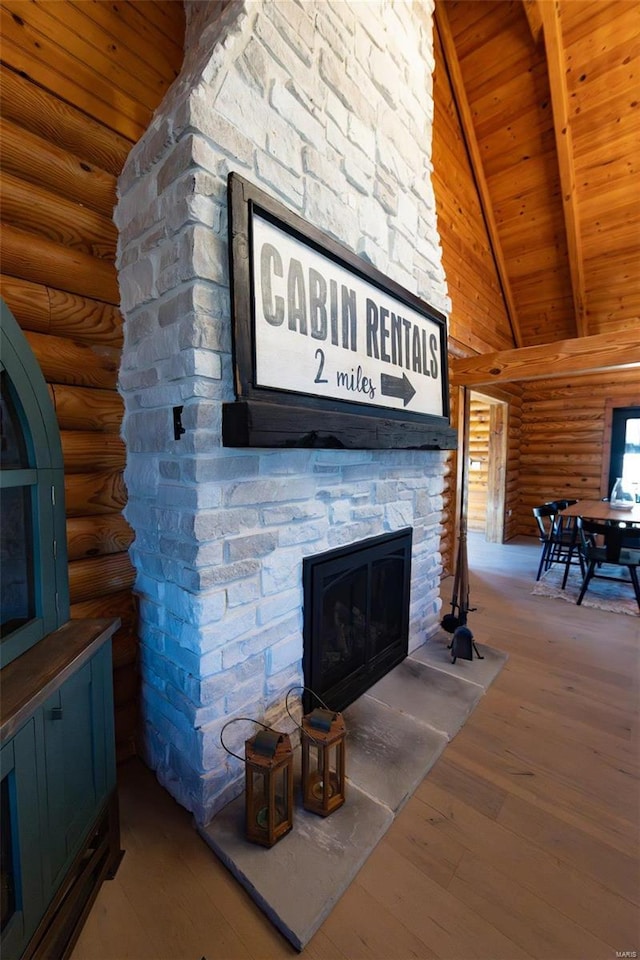 details with beamed ceiling, a stone fireplace, wooden ceiling, wood finished floors, and rustic walls