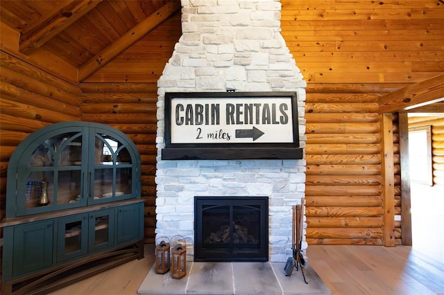 living room featuring beamed ceiling, high vaulted ceiling, wood finished floors, a stone fireplace, and wooden ceiling