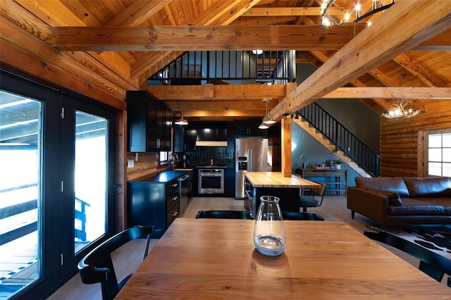 dining space with beam ceiling, an inviting chandelier, stairway, and log walls