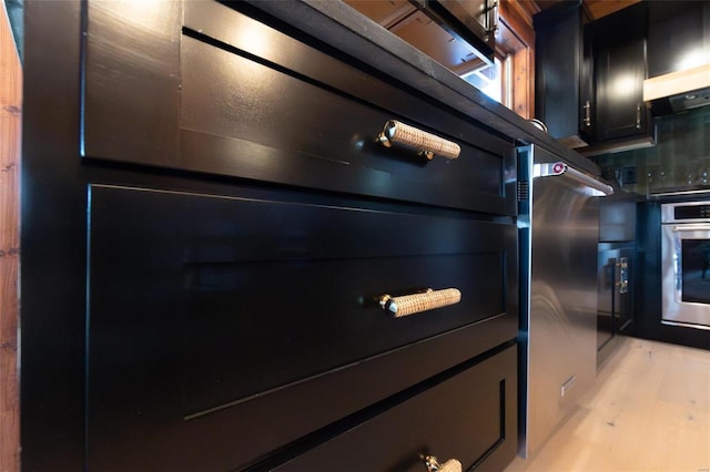 details featuring decorative backsplash, light wood-style floors, and dark cabinets