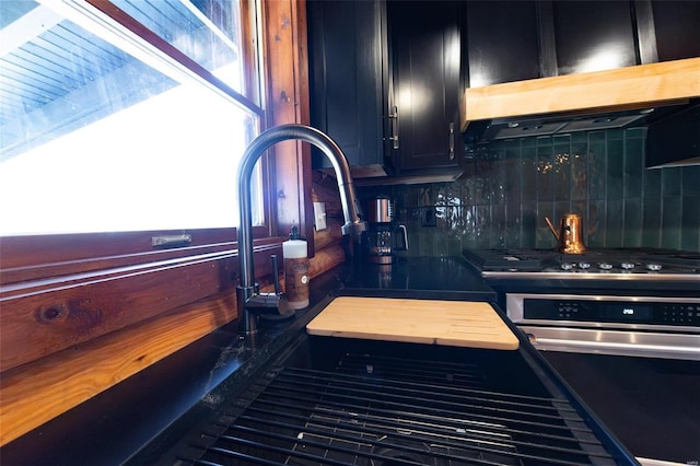 kitchen with ventilation hood, decorative backsplash, and dark cabinets