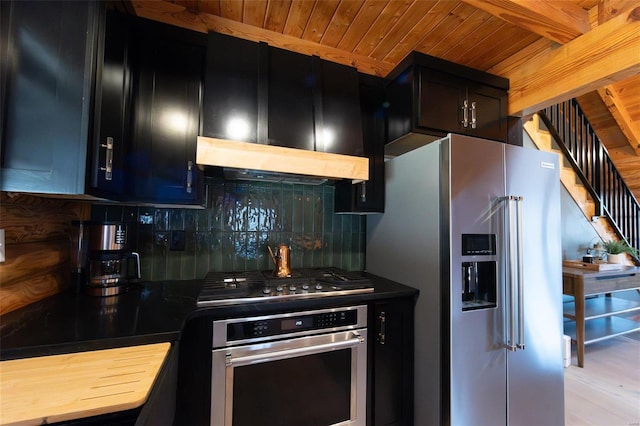 kitchen with tasteful backsplash, under cabinet range hood, wooden ceiling, dark cabinetry, and stainless steel appliances