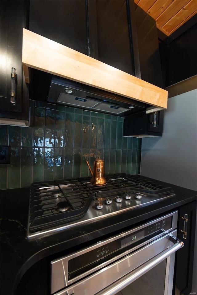 room details featuring dark cabinets, backsplash, and exhaust hood