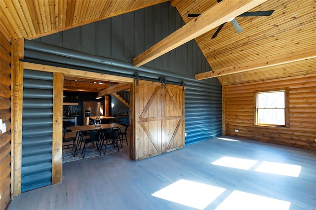 interior space featuring wood finished floors, high vaulted ceiling, a barn door, wooden ceiling, and rustic walls