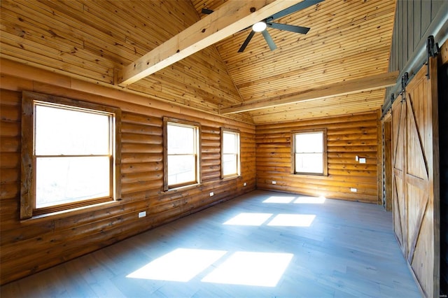 empty room featuring a barn door, hardwood / wood-style flooring, wood ceiling, and high vaulted ceiling