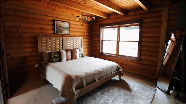 bedroom featuring log walls, wood finished floors, beamed ceiling, and wooden ceiling