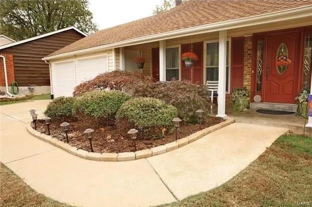 exterior space with concrete driveway, an attached garage, and a shingled roof