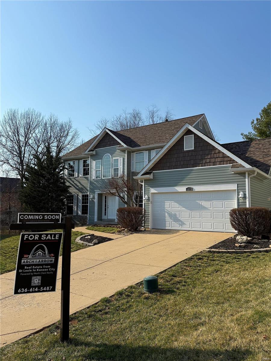 view of front of home with a garage, concrete driveway, and a front yard