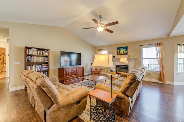 living room featuring a fireplace, baseboards, ceiling fan, dark wood-style flooring, and vaulted ceiling