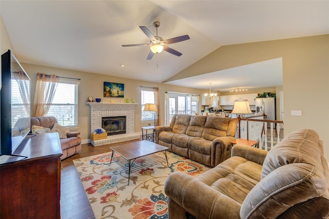 living room featuring vaulted ceiling, wood finished floors, ceiling fan with notable chandelier, and a healthy amount of sunlight