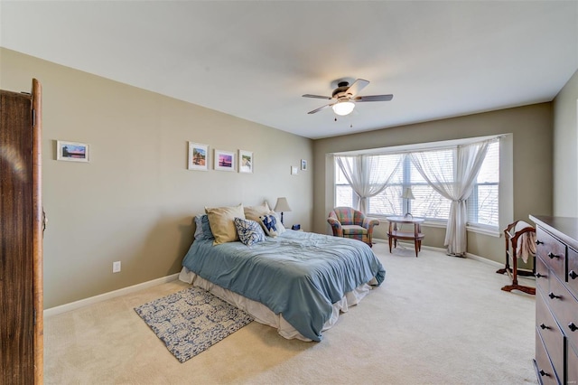 bedroom featuring light carpet, a ceiling fan, and baseboards