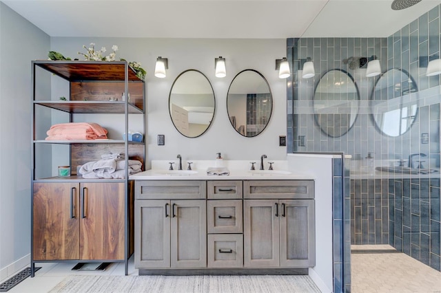 bathroom featuring a tile shower, double vanity, and a sink