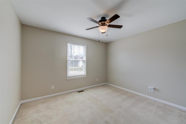 empty room with light carpet, visible vents, baseboards, and ceiling fan