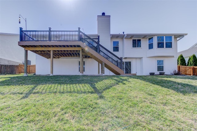 back of property with fence, a wooden deck, stairs, a lawn, and a chimney