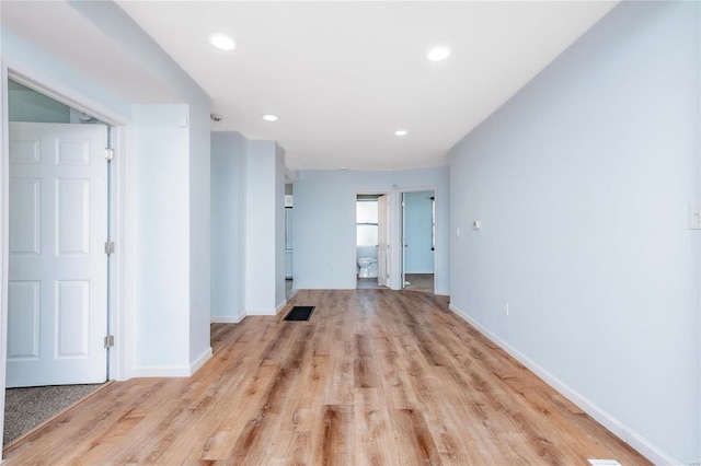 corridor with light wood-style flooring, recessed lighting, visible vents, and baseboards