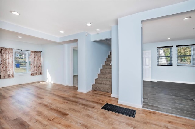 unfurnished living room featuring stairway, recessed lighting, and wood finished floors