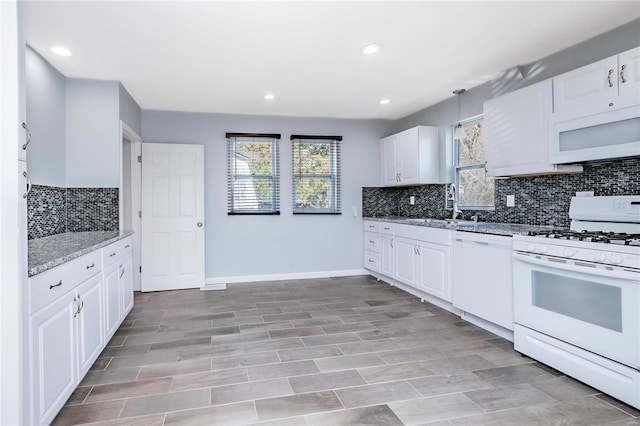 kitchen with white appliances, white cabinets, light stone countertops, and backsplash