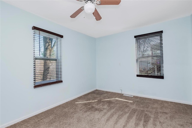 carpeted empty room featuring ceiling fan and baseboards