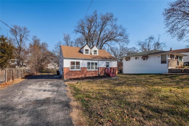 view of front of property with aphalt driveway, fence, brick siding, and a front yard