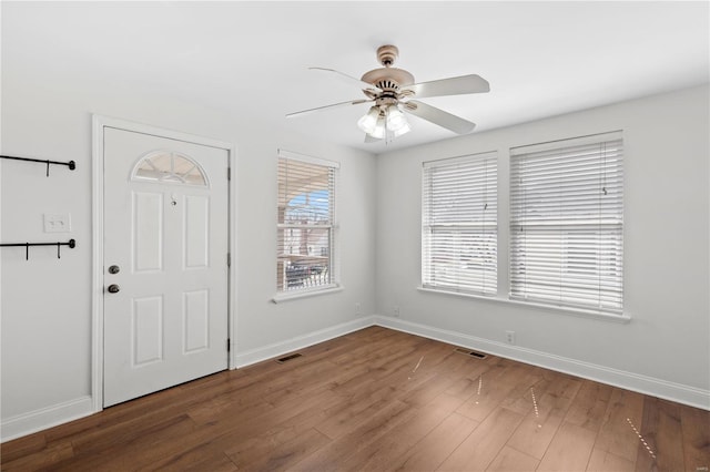 foyer with ceiling fan, visible vents, baseboards, and wood finished floors