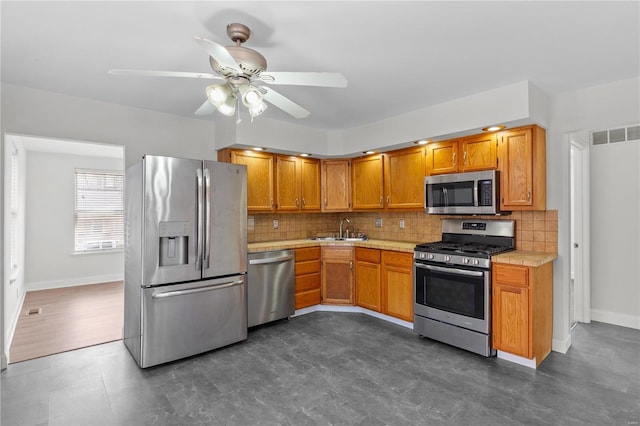 kitchen with tasteful backsplash, appliances with stainless steel finishes, light countertops, and a sink