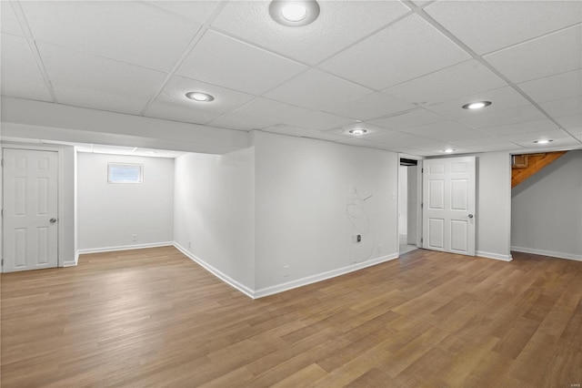 finished below grade area with recessed lighting, light wood-style flooring, a paneled ceiling, and baseboards