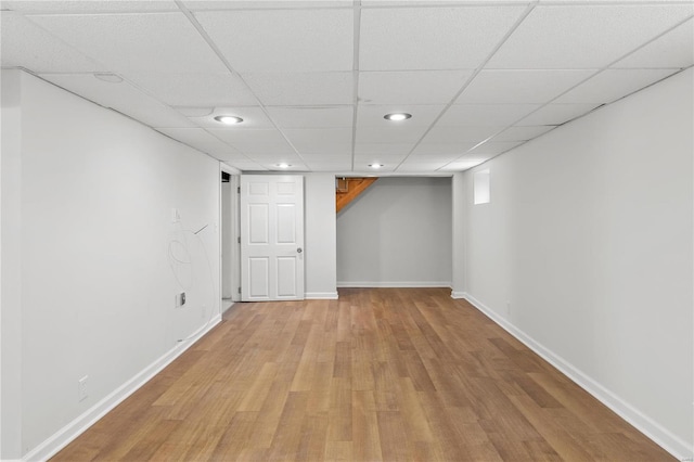 finished basement featuring recessed lighting, light wood-type flooring, baseboards, and a drop ceiling