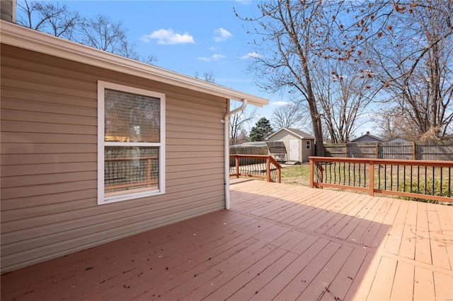 wooden deck featuring a storage shed, an outbuilding, and a fenced backyard