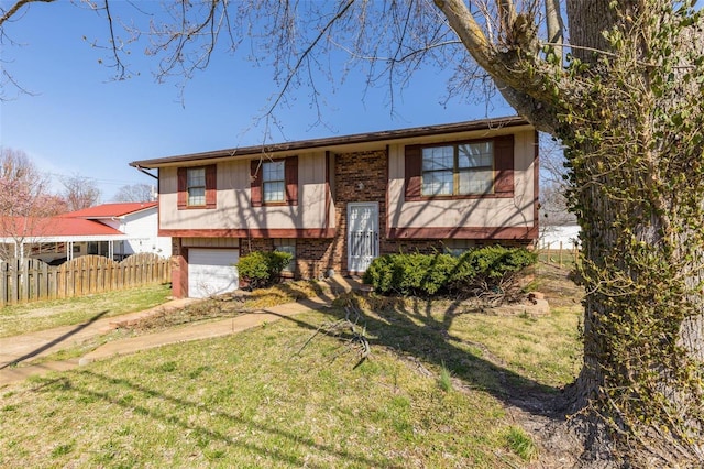 split foyer home with brick siding, a front yard, a garage, and fence