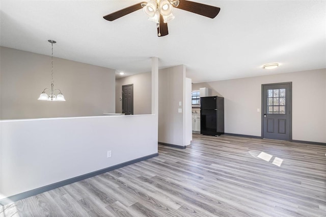 unfurnished living room with baseboards, wood finished floors, and ceiling fan with notable chandelier