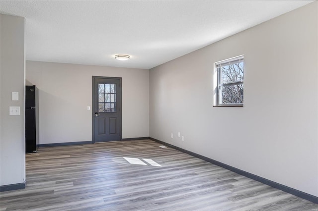 interior space with a healthy amount of sunlight, a textured ceiling, baseboards, and wood finished floors