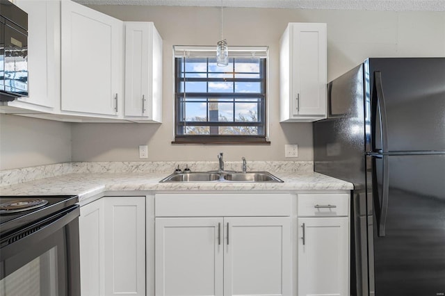 kitchen featuring black appliances, a sink, decorative light fixtures, white cabinetry, and light countertops