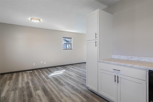 interior space featuring wood finished floors, baseboards, and a textured ceiling