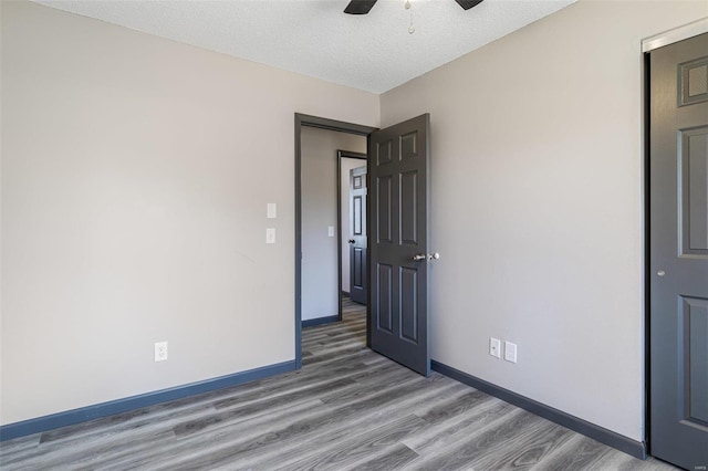 spare room featuring ceiling fan, baseboards, and wood finished floors