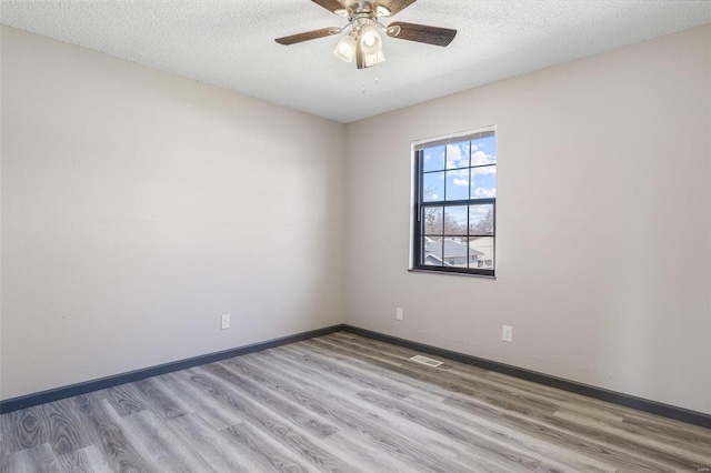 empty room with ceiling fan, wood finished floors, visible vents, and a textured ceiling