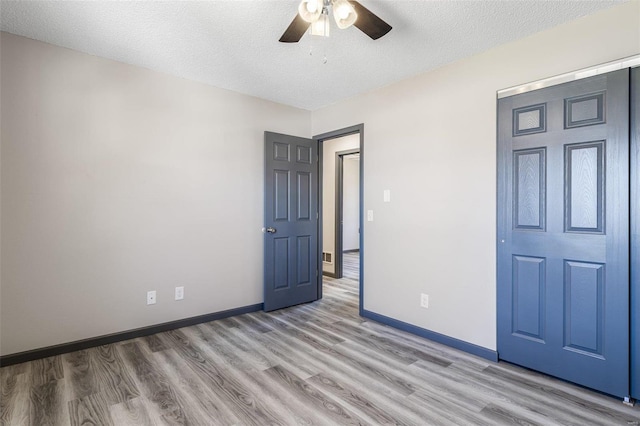 unfurnished bedroom with ceiling fan, a textured ceiling, light wood-style floors, and baseboards