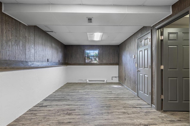 below grade area featuring visible vents, wood walls, and wood finished floors