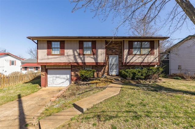 raised ranch featuring a front yard, fence, driveway, an attached garage, and brick siding