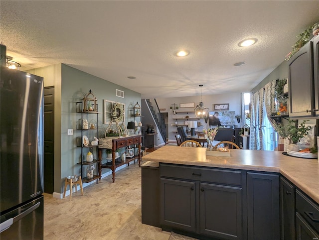 kitchen featuring visible vents, light countertops, a peninsula, freestanding refrigerator, and a textured ceiling