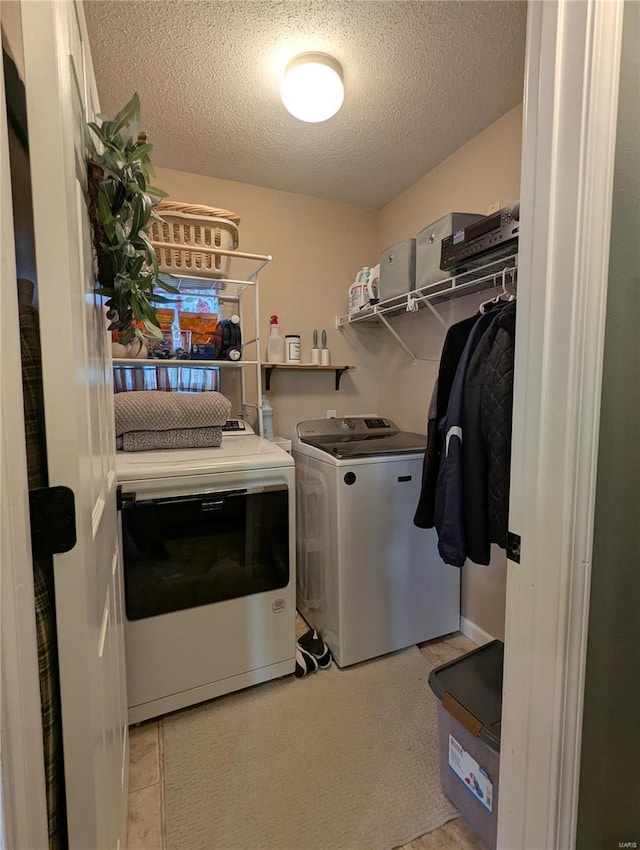 clothes washing area with a textured ceiling, laundry area, and washer and clothes dryer