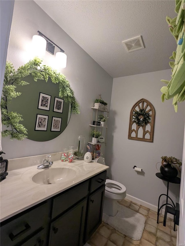 half bathroom with visible vents, toilet, a textured ceiling, baseboards, and vanity