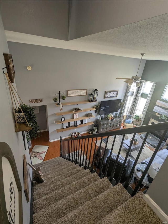 staircase featuring ceiling fan, wood finished floors, and a textured ceiling