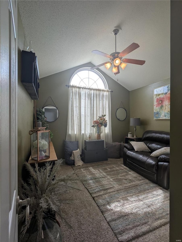 carpeted living room featuring a textured ceiling, lofted ceiling, and a ceiling fan