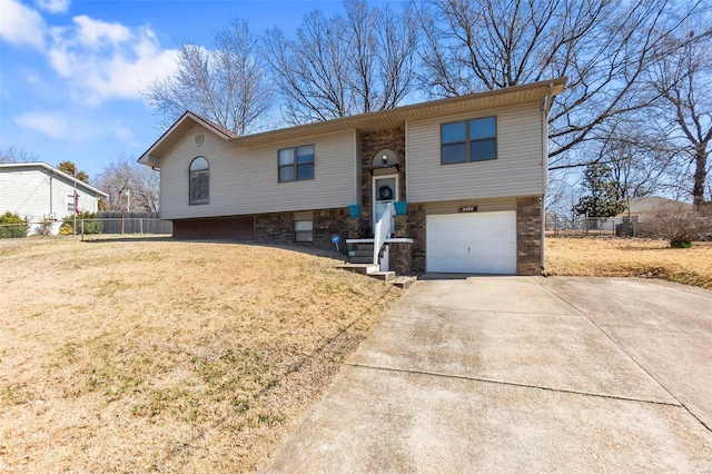 split foyer home with driveway, a front yard, a garage, and fence